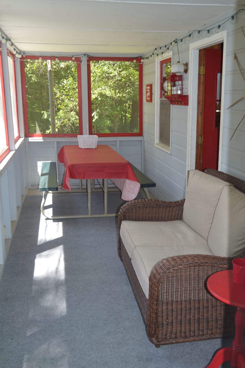 Screened in porch with a picnic table, double rocker overlooking the lake