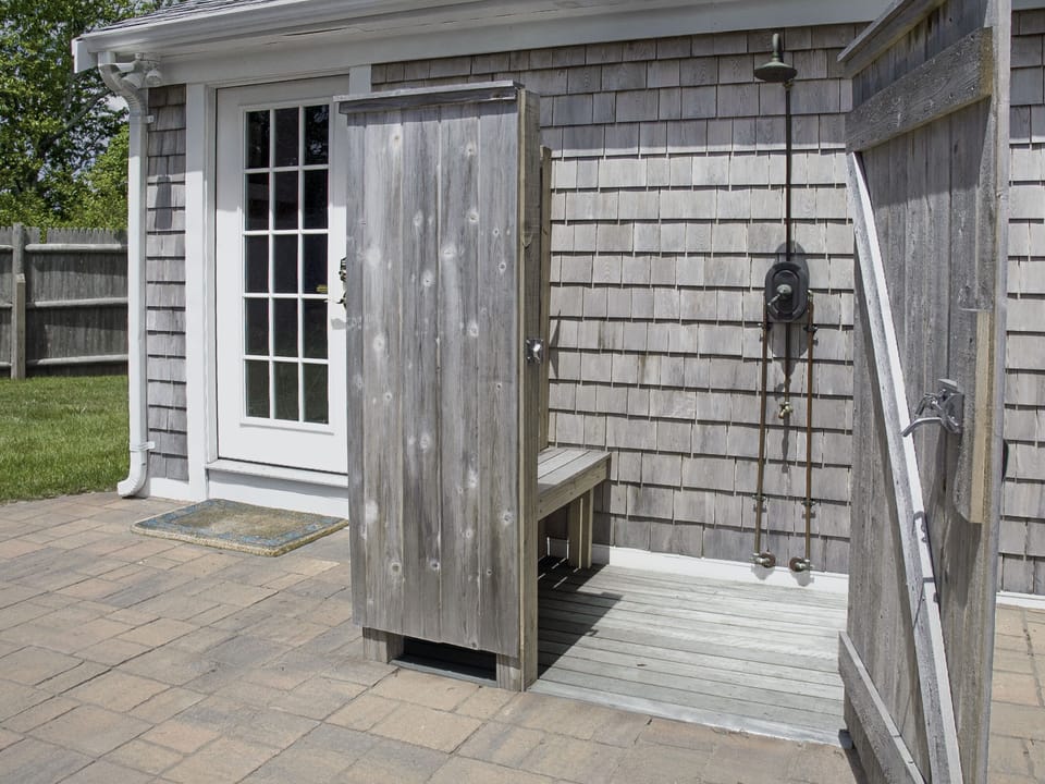 Outdoor shower has smooth mahogany bench & deck and no step from the patio