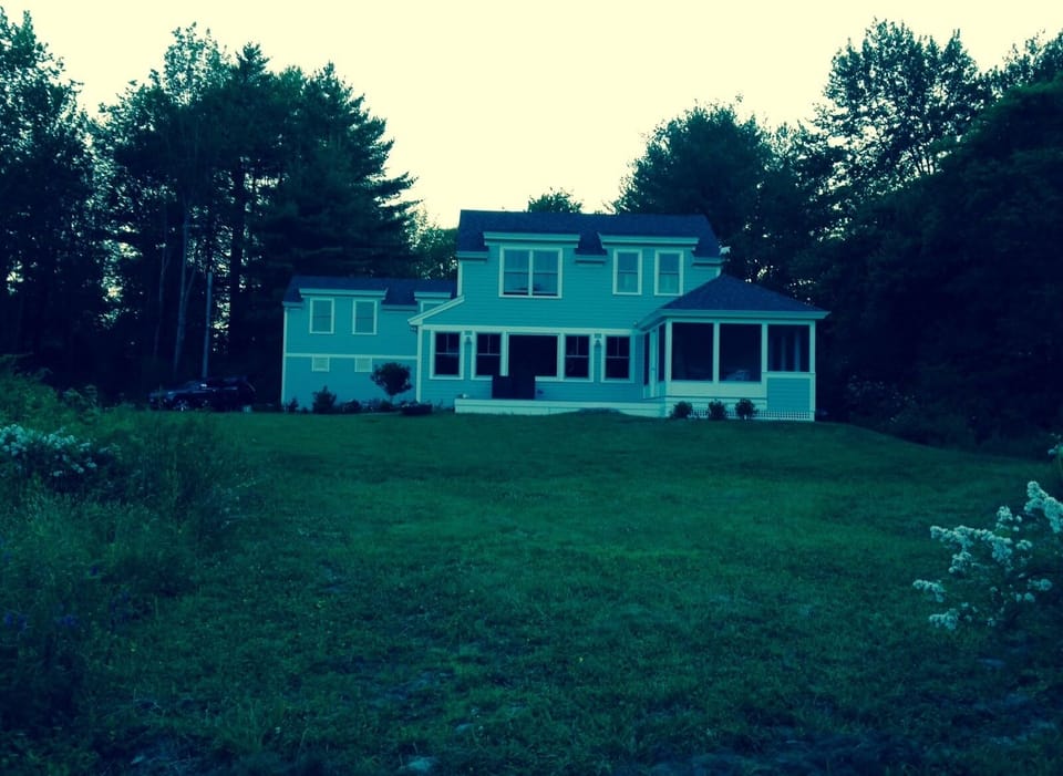 Few of the side of the house with porch and deck as seen from the dock. 