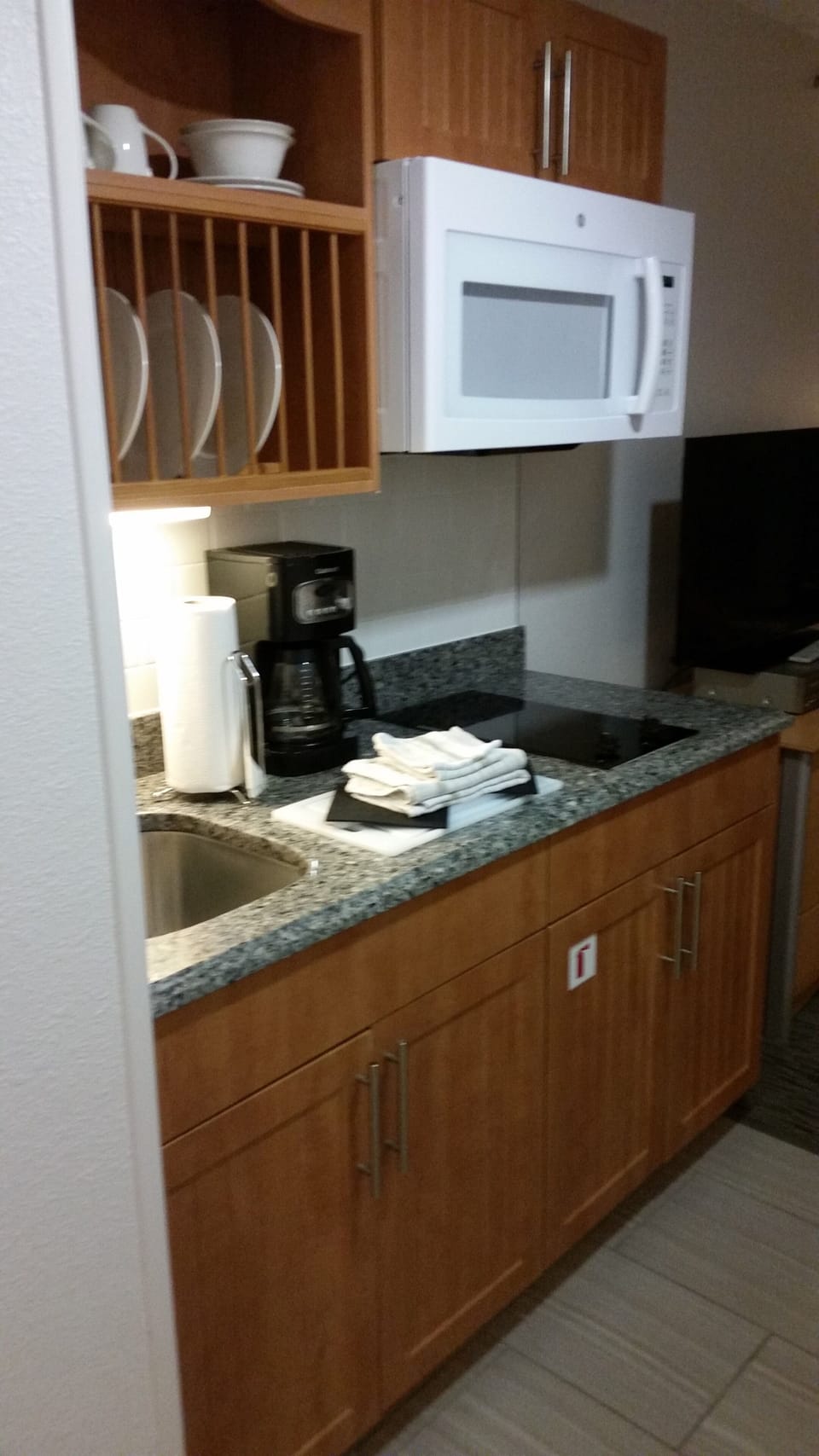 Small kitchen with mini stove, microwave, dishes, and coffee maker