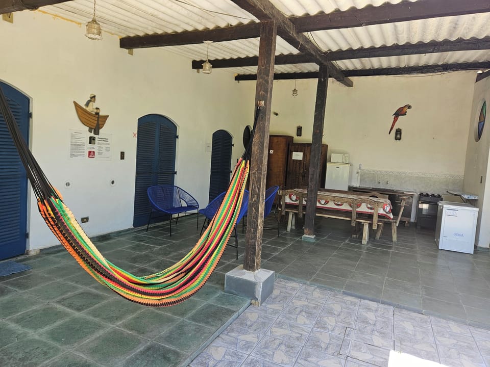 Área externa com rede, jogo de móveis Acapulco e cozinha.