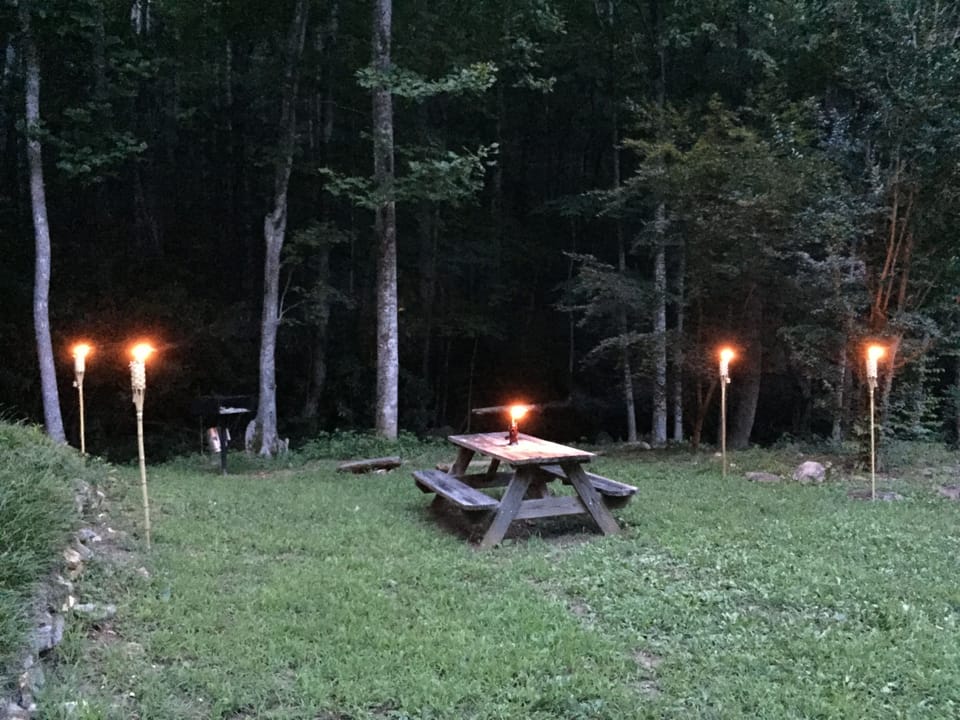 Picnic area with charcoal grill next to stream.