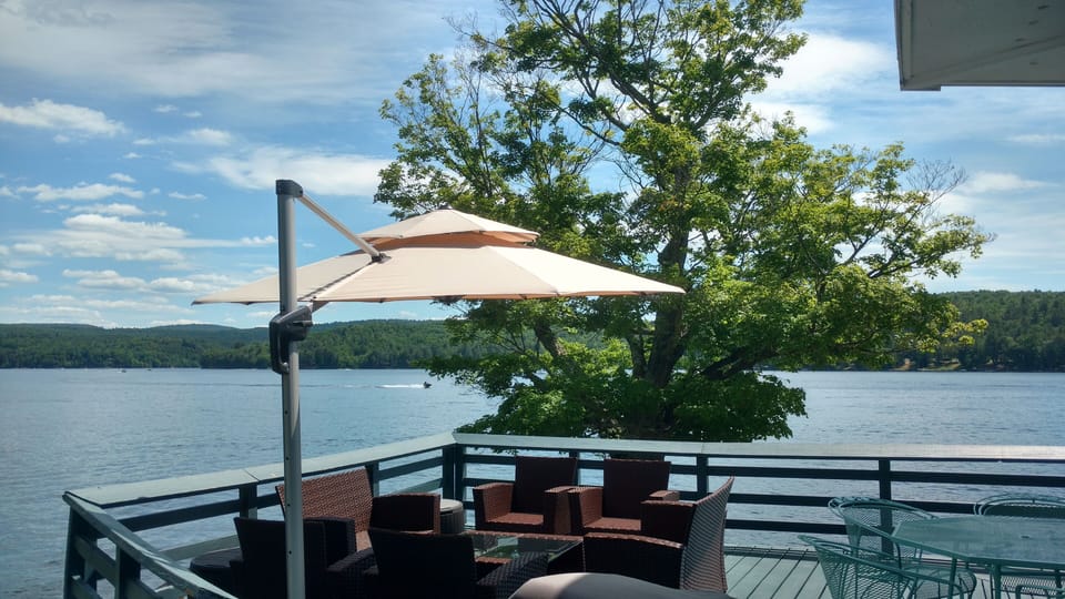 Large deck overlooking the lake w/ plenty of furniture and  cantilever umbrella