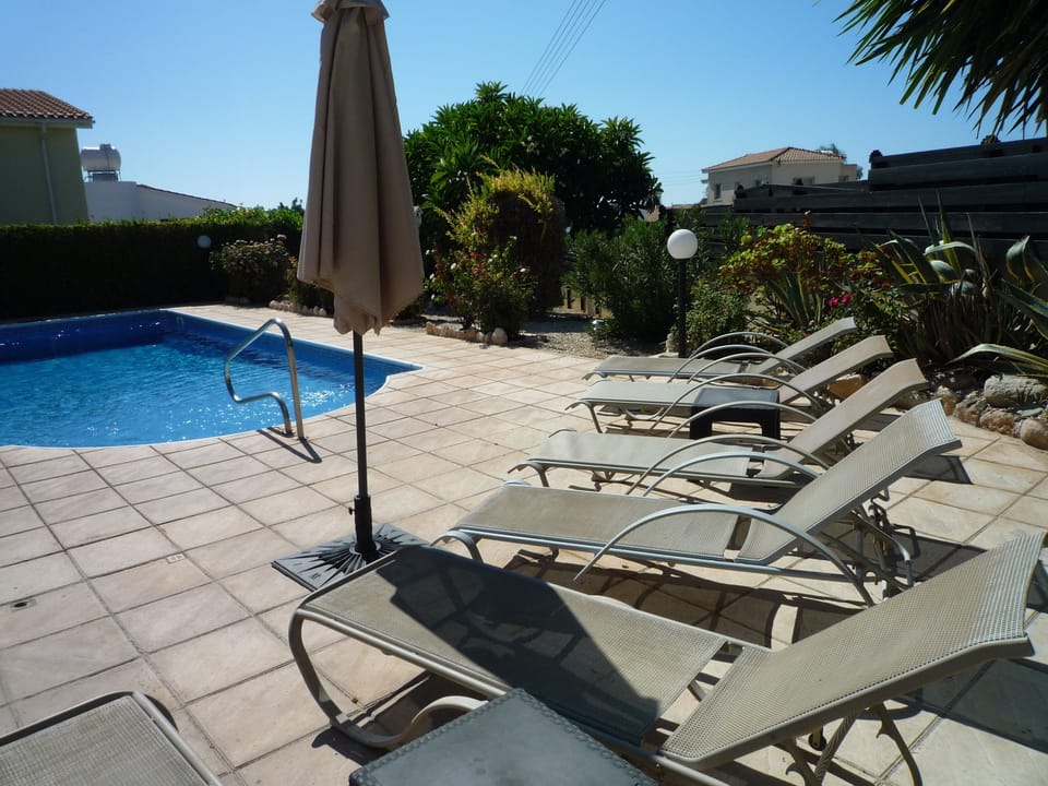 Large sun bathing area next to pool and BBQ.