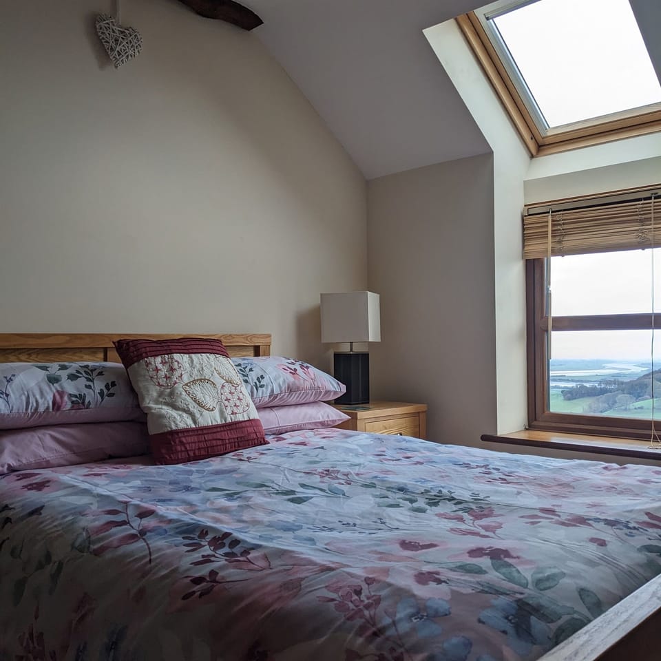 This is our master bedroom with exposed beams and en-suite with far reaching views of the countryside and River Severn.