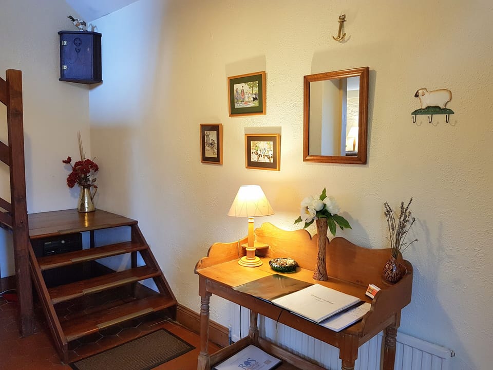 The cottage hallway has a high ceiling and stairs to Main Bedroom