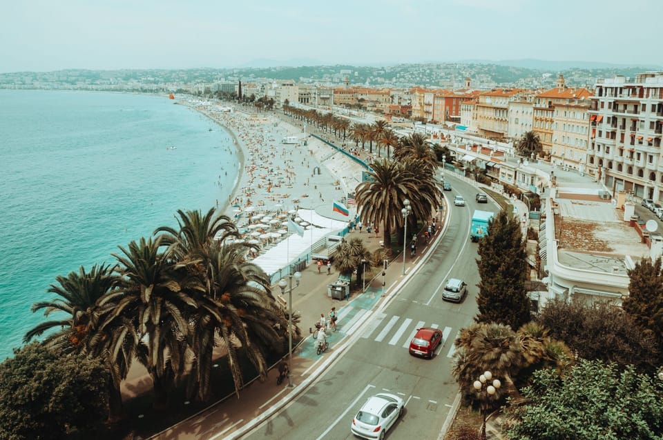 Palm-lined Promenade des Anglais sweeps along Nice's famous shingle beach, with sunbathers and the sparkling Mediterranean stretching into the distance.
