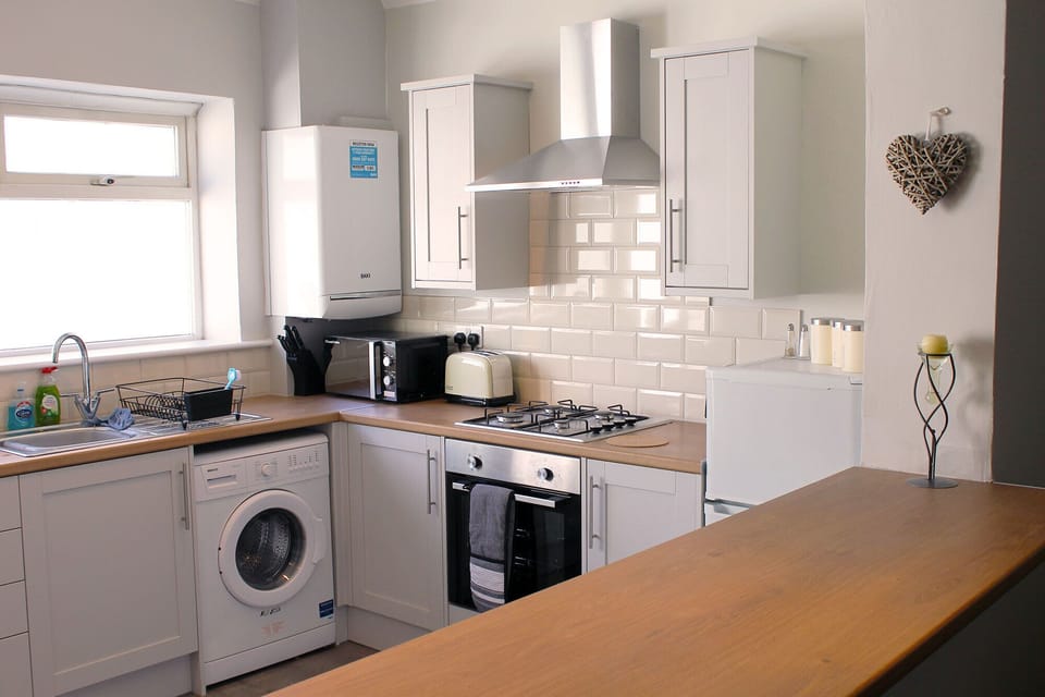 Modern kitchen with fridge, washing machine and other amenities.