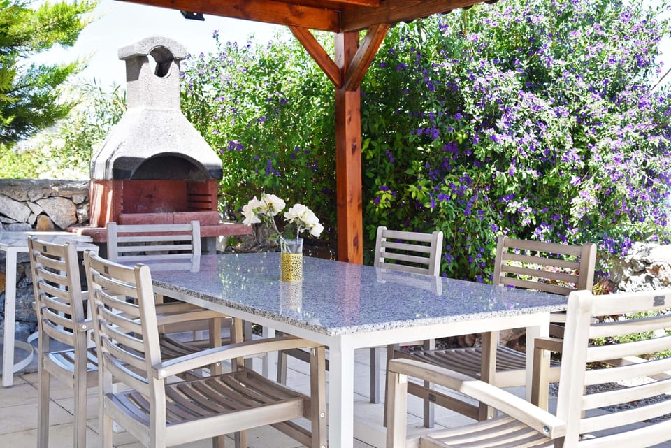 Barbecue area with grant table and bougainvillea plant