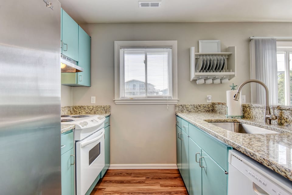Clean kitchen with newly painted cabinets, new refrigerator, & granite counters.