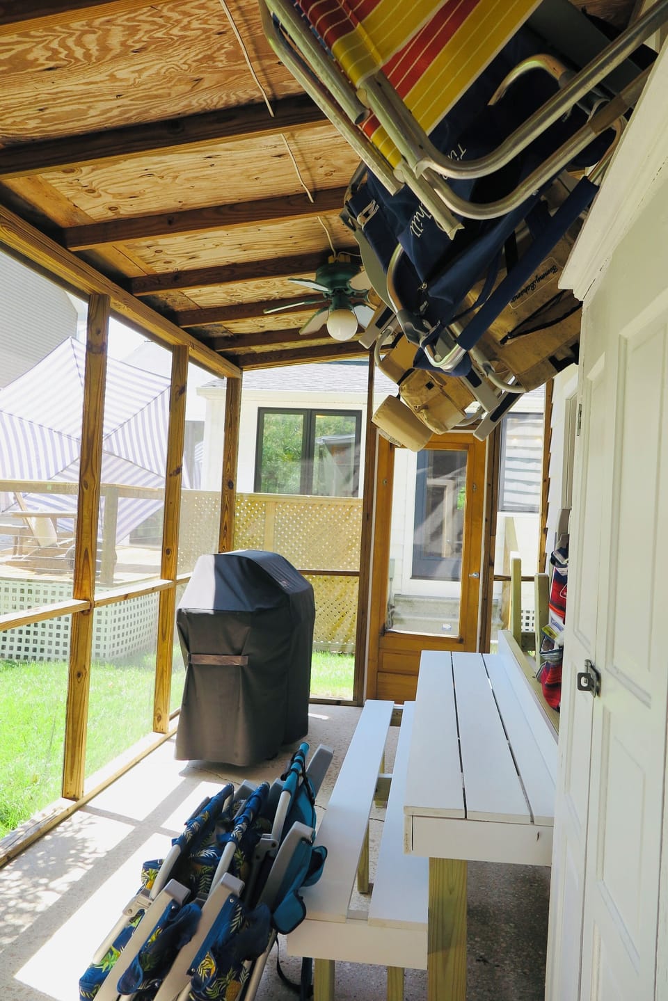 Screened porch (taken from shower)  with chairs and grill facing house.
