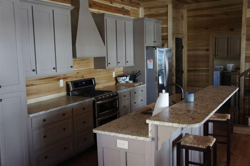 The kitchen features granite counter tops, a large bar area, and gas cook top.