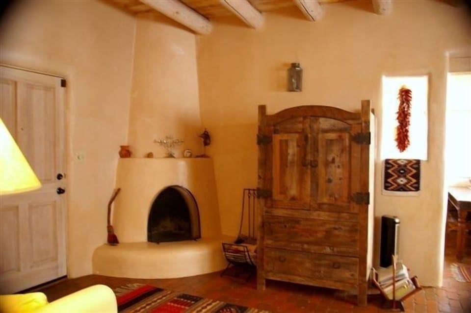 Cozy kiva fireplace, colorful mexican rugs, and ristras in the living room.