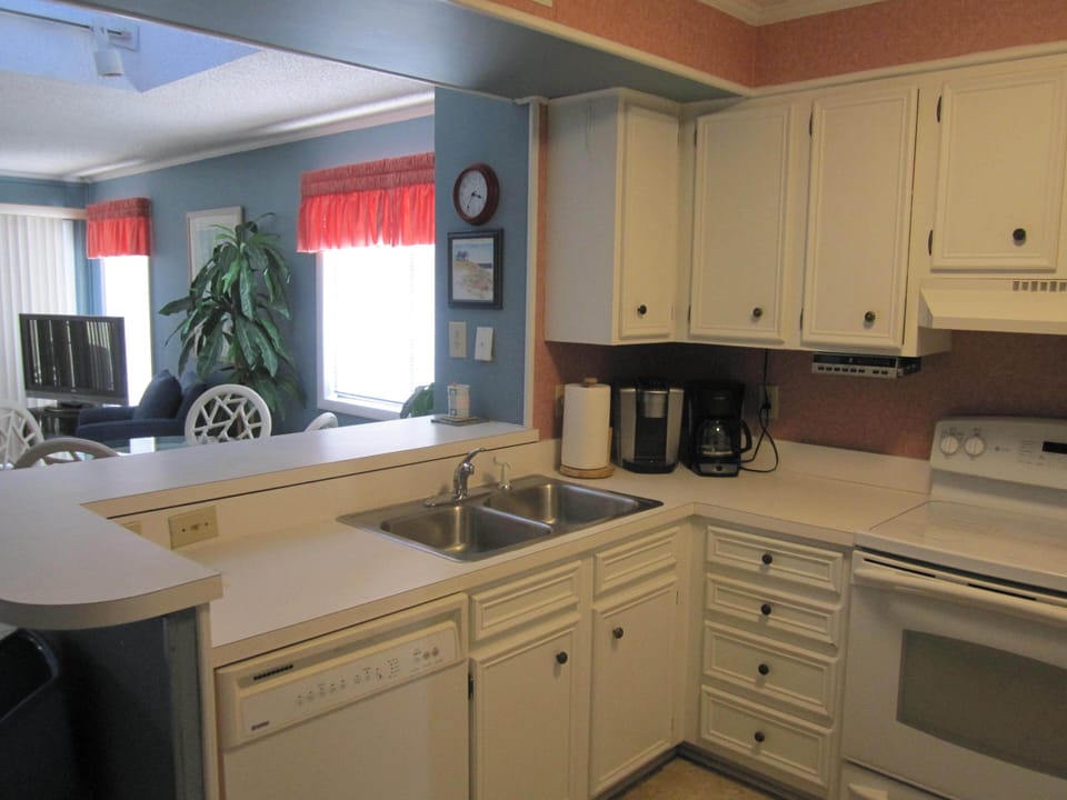 Fully equipped kitchen overlooking living room and dining area.