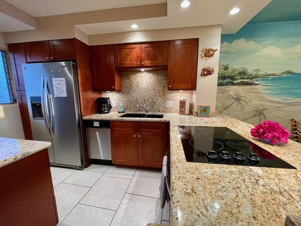 Kitchen includes full size refrigerator, compact dishwasher, and glass cook top