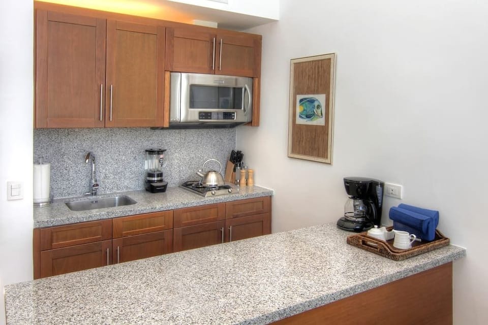Kitchen area with microwave, coffee maker, stove top, refrigerator
