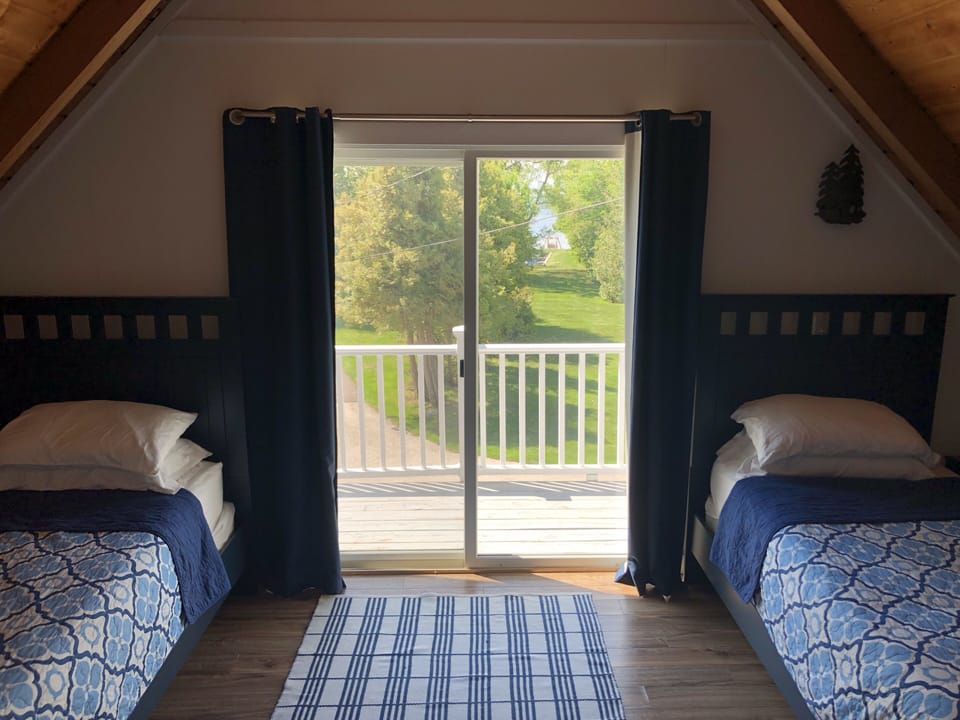Twin bedroom looking out to the upstairs balcony. AC unit & ceiling fan in room.
