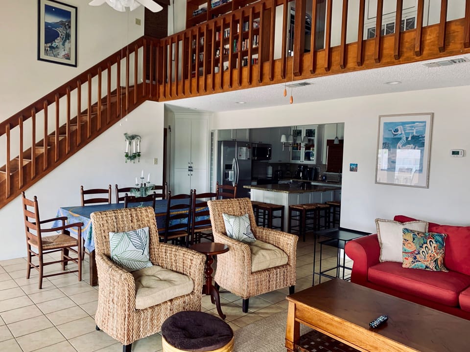 View of upstairs walkway with library, dining and living rooms and kitchen.