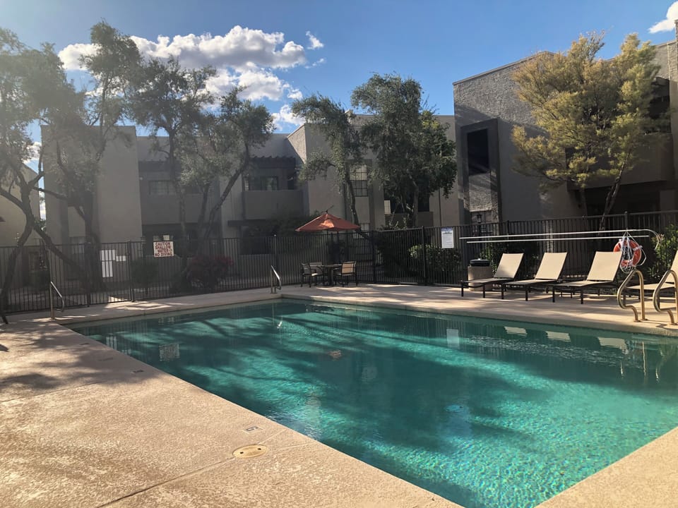 Large outdoor pool with shallow end, plenty of chairs and grill nearby