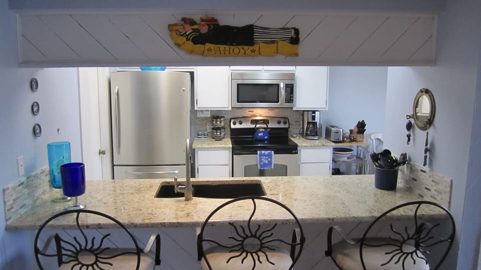 Kitchen has granite countertops, stainless steel appliances, and barstools