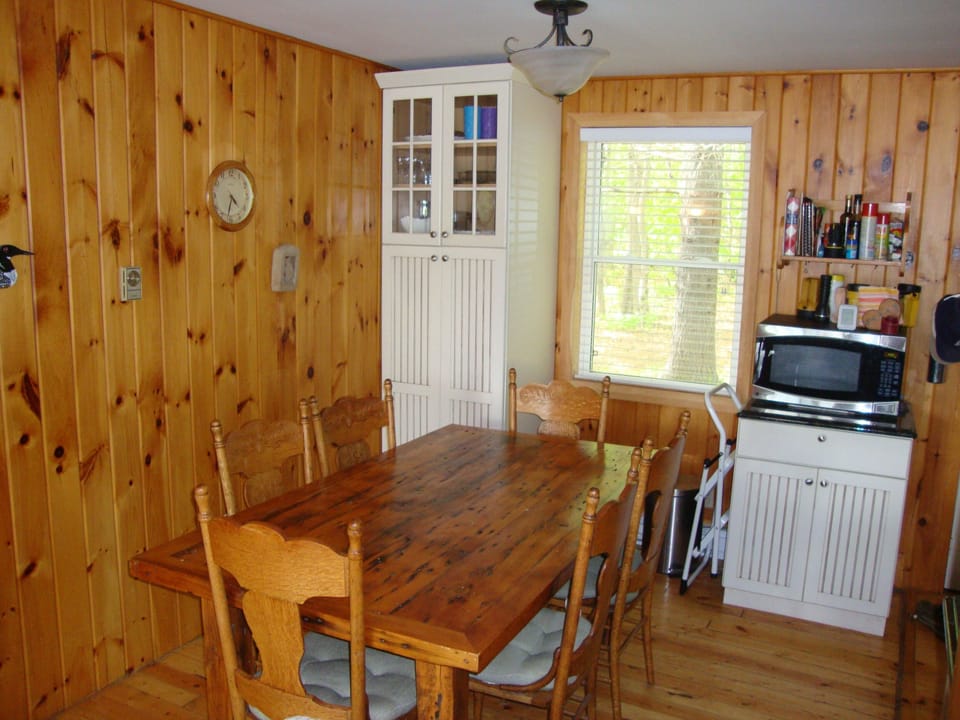 Dining table adjacent to kitchen seats six. Three nearby barstools at counter.