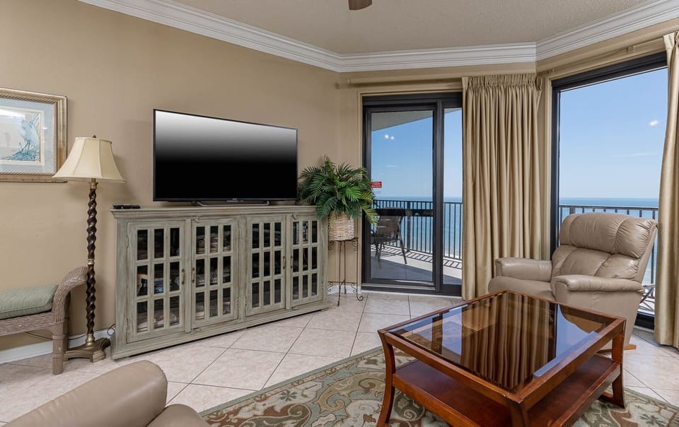 Cozy living area features a TV, sofa with queen sleeper, elegant coffee table, and access to a gulf front balcony