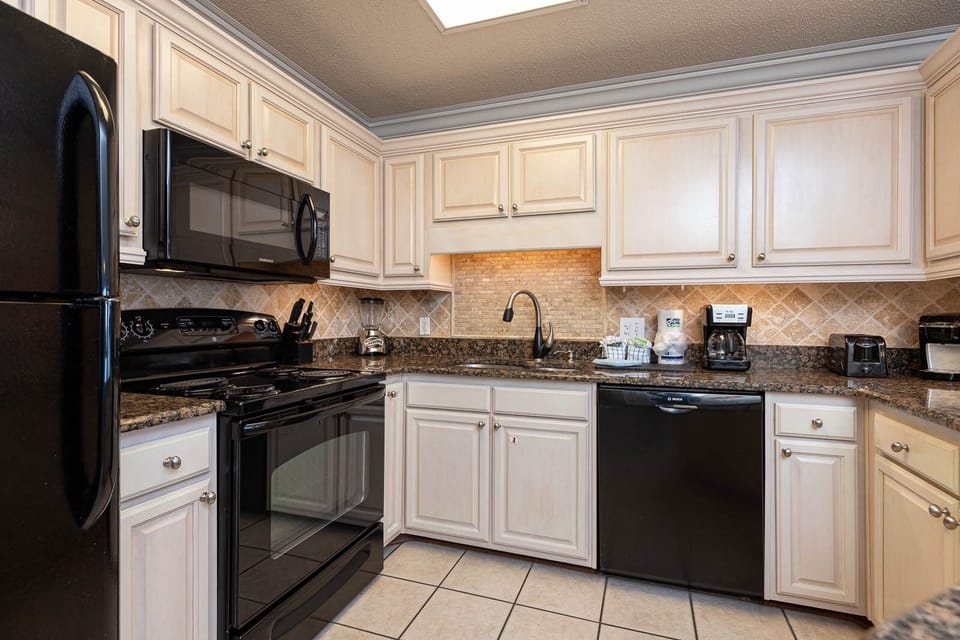 The kitchen features black appliances, light cabinetry, and granite countertops, creating an inviting cooking space