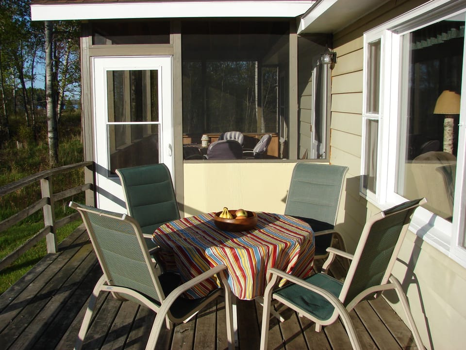 Table on the front deck, screen porch with another table in back ground
