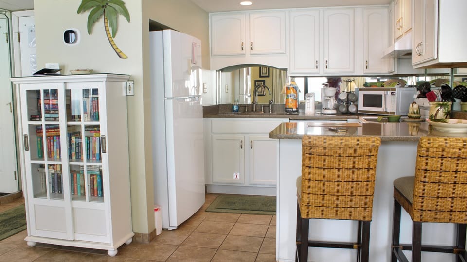 A bookcase full of good beach reads and a  kitchen bar to enjoy a snack.