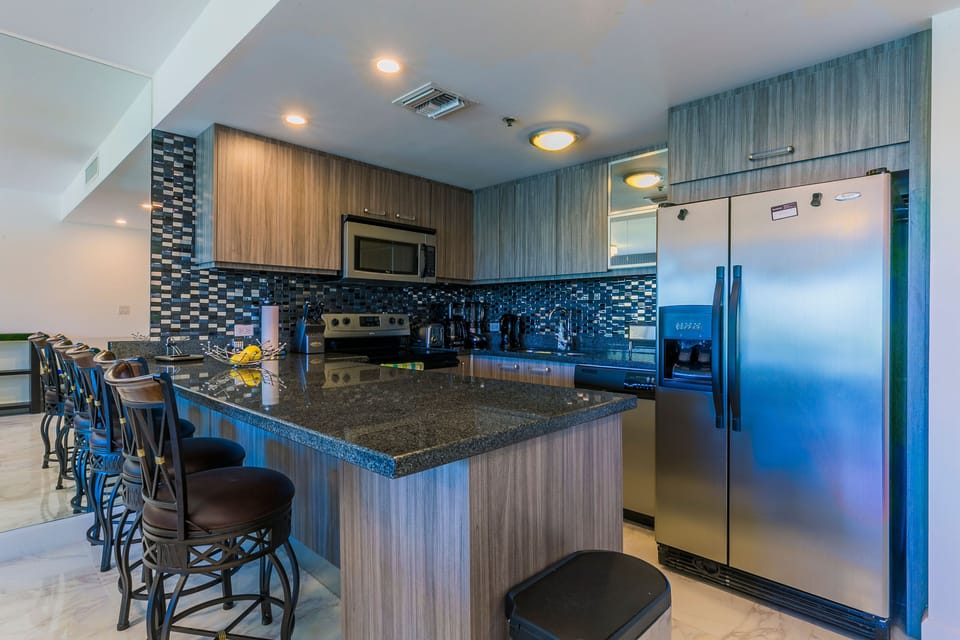 Gather around the granite-topped island in your fully equipped kitchen, complete with stainless steel appliances and stylish tile backsplash. Every modern convenience awaits for your meals together.