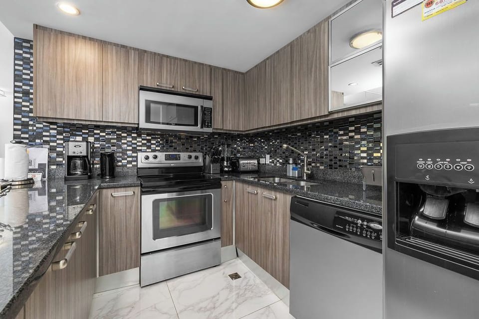 Your fully equipped kitchen features sleek granite countertops, stainless appliances, and a stylish mosaic backsplash—perfect for preparing meals and starting your mornings with fresh coffee.