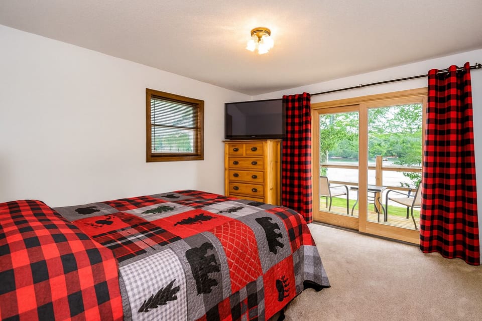 Primary suite with king bed, custom log furniture, and lake views — peaceful mornings by the water.