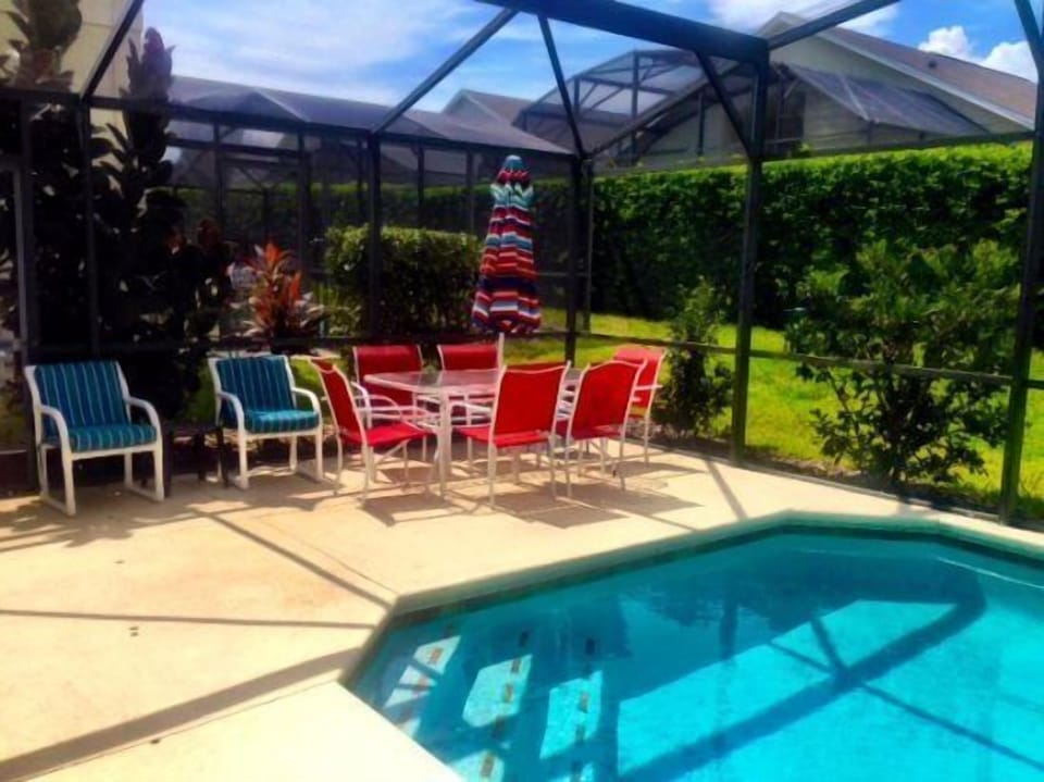 Lush and private pool area with grass to play, dining area, umbrella, loungers