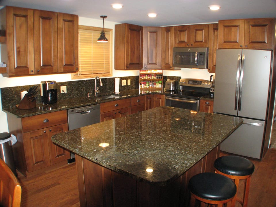 Granite top with barstool seating, washer and dryer under island top.