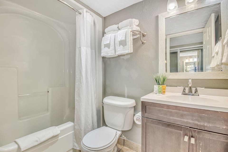 Experience classic comfort in our bathroom, equipped with a timeless bathtub, a functional sink, and a toilet, offering a cozy and familiar setting.