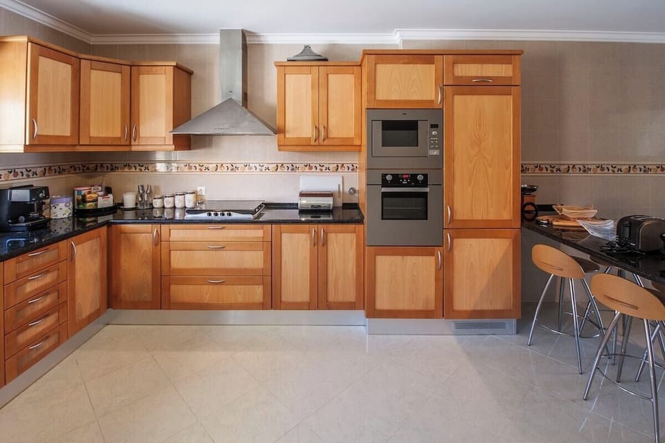 Modern kitchen with wooden cabinetry and stainless steel appliances — Villa Salsa, holiday villa in Mafra