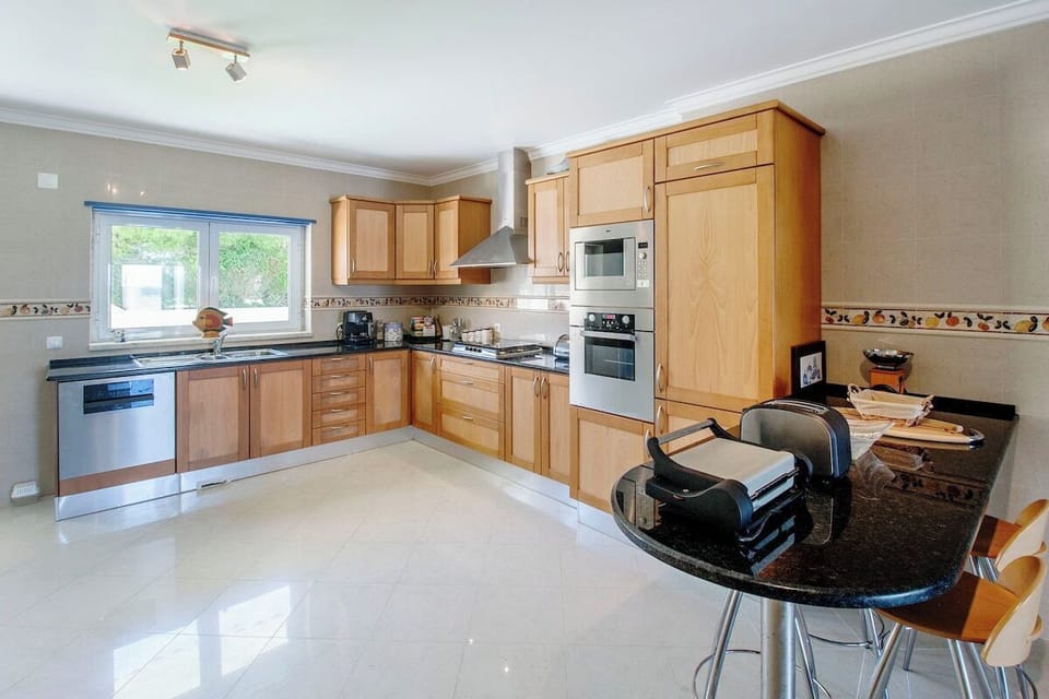 Spacious open-plan kitchen with wooden cabinetry and black granite countertops — Villa Salsa, luxury holiday villa in Mafra