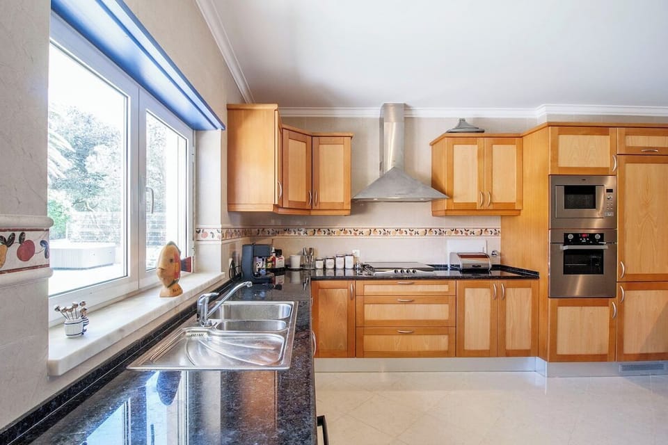 Modern kitchen with wooden cabinetry and dark granite countertops — Villa Salsa, luxury holiday villa in Mafra