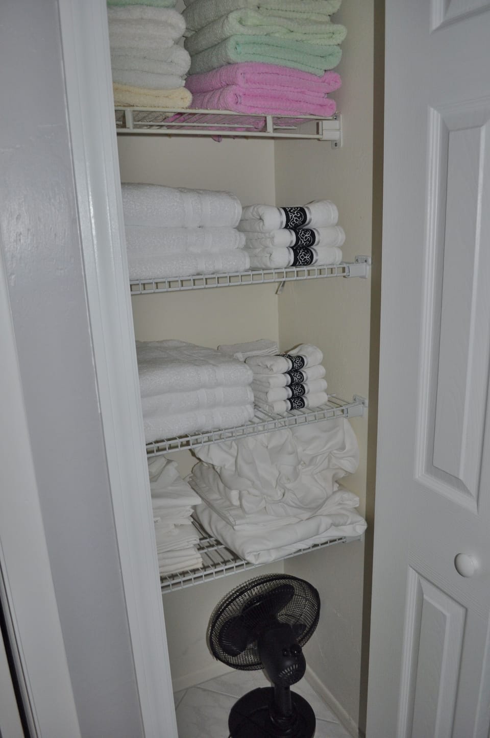 Linen closet has lots of towels, extra sheets and a fan