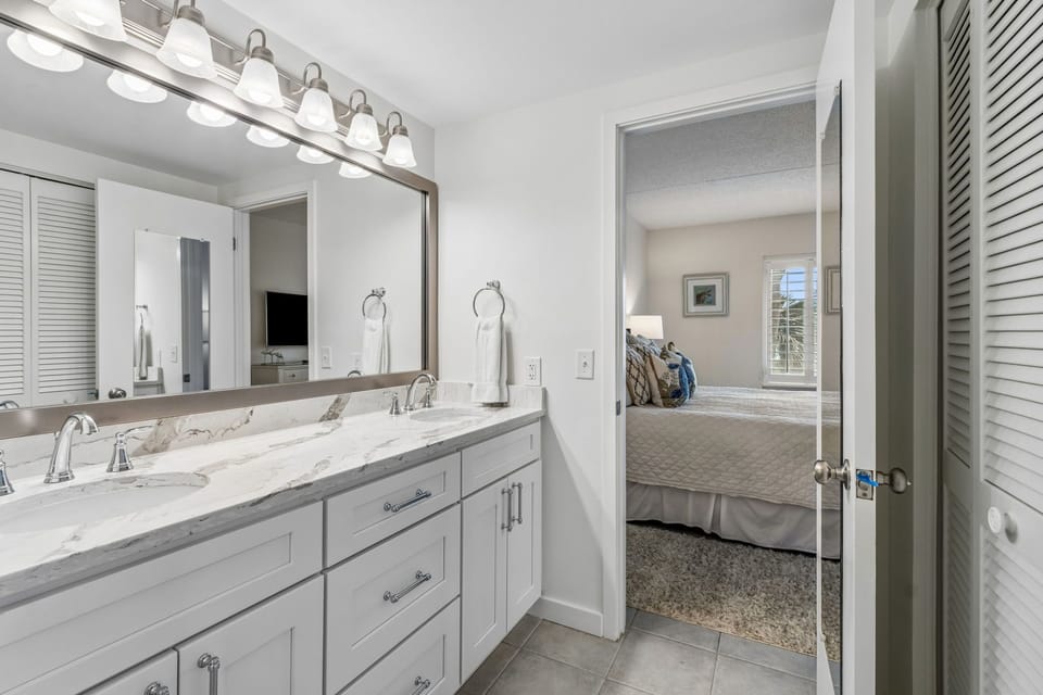 Master Bathroom with Double Sinks, Quartz Countertops, and a Tiled Walk In Shower
