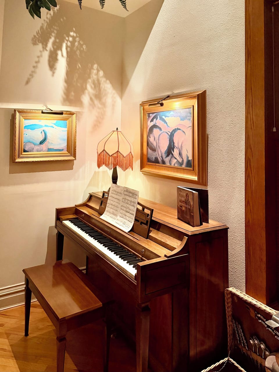 Spinet piano with sheet music in seat bench.