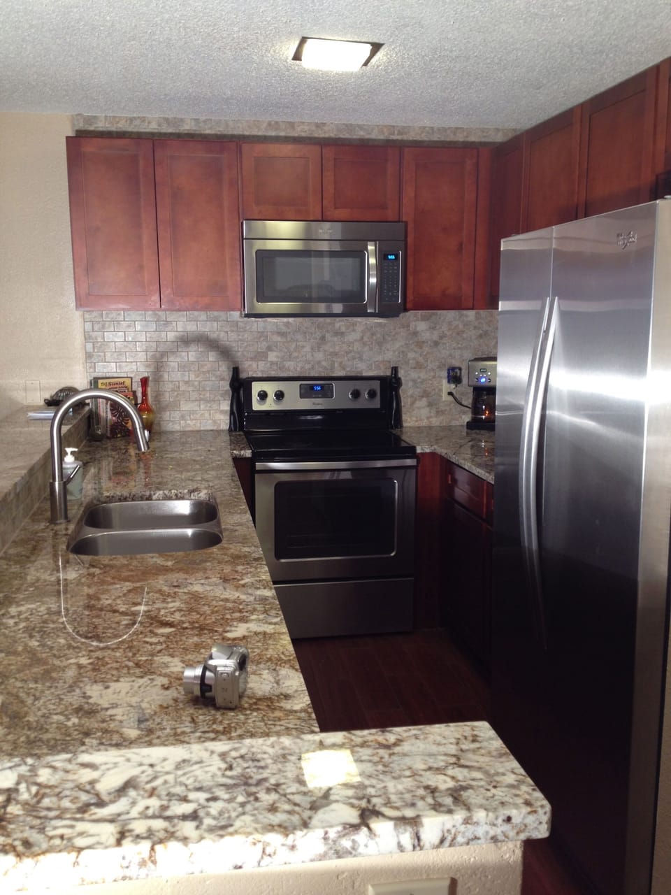 Kitchen has stainless steel appliances cherry cabinets and granite counter tops.