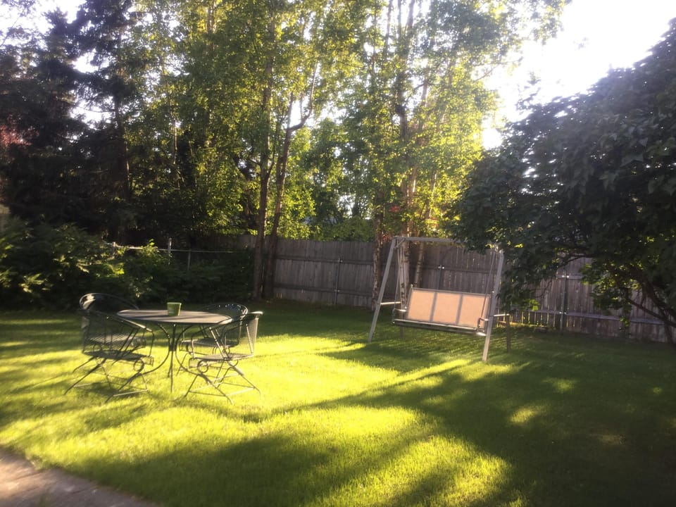 Backyard has a swing bench, a hammock, a table and a croquet set. 