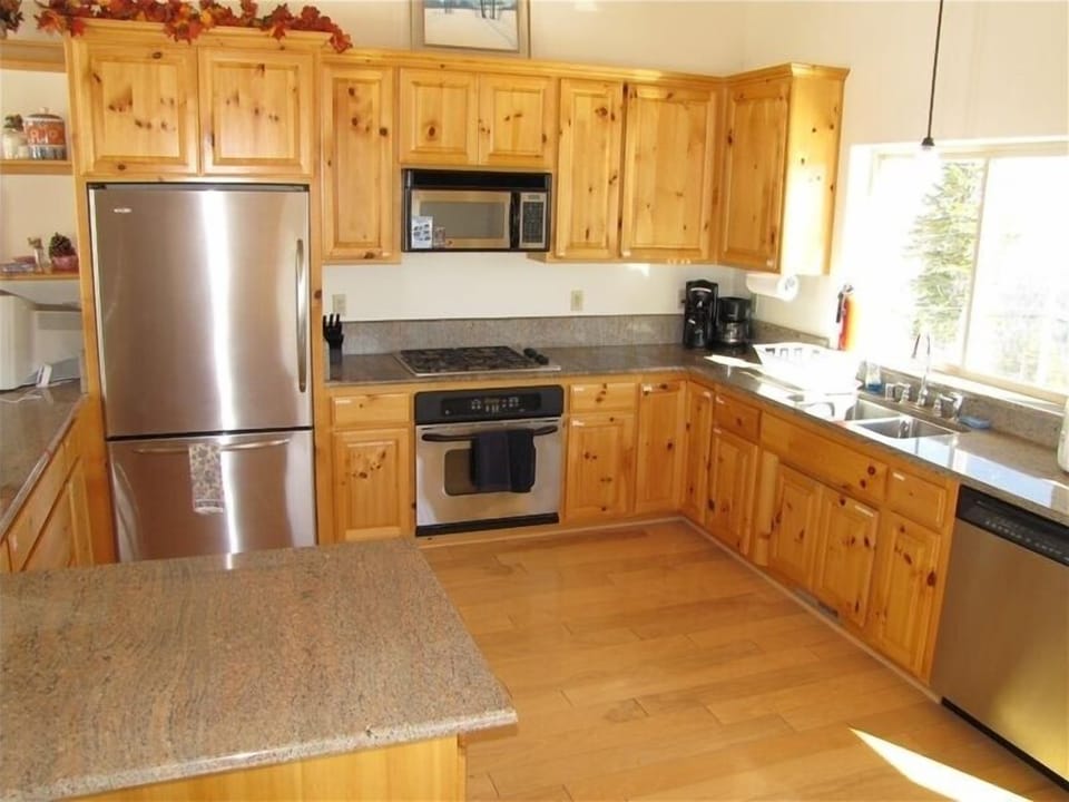 Kitchen with stainless steel appliances and slab granite countertops.