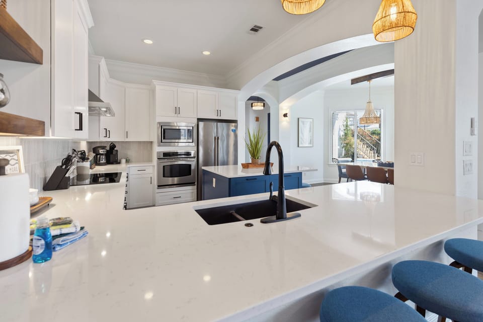 Prepare meals in your gleaming chef's kitchen featuring quartz countertops, stainless steel appliances, and a stylish blue island for gathering.