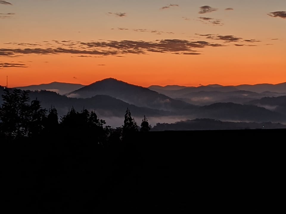 - Fiery sunset painting the Smoky Mountain skyline with warm orange hues   - Evening calm settles as golden light fades behind distant ridges   - The perfect end to a day surrounded by mountain peace and beauty