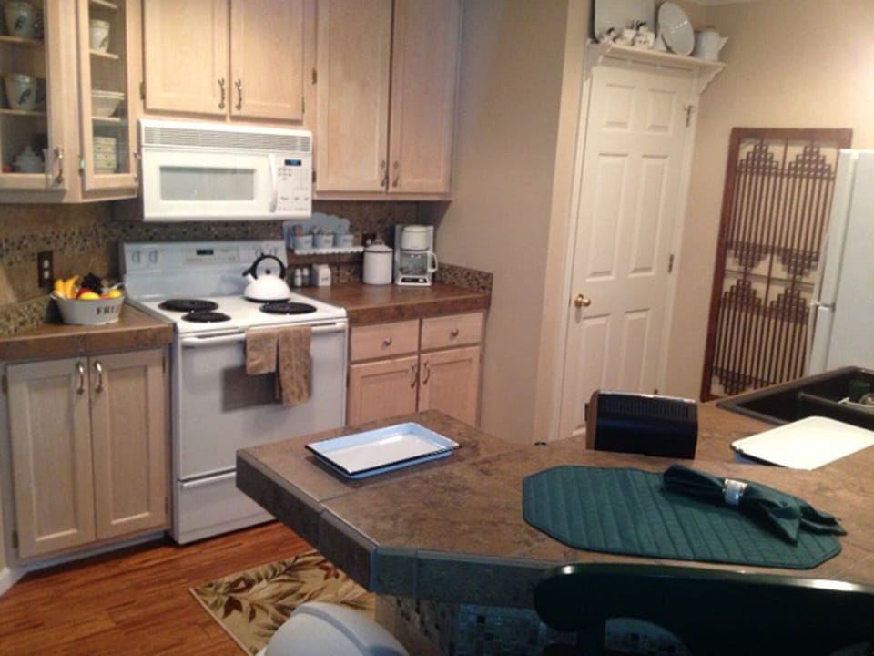 Kitchen is stocked with dinnerware, utensils and serving ware for meals.
