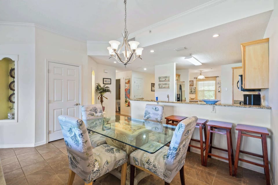 - Stylish dining space featuring glass table and cushioned chairs  
- Chandelier lighting adds charm and warmth to the open layout  
- Conveniently located next to the kitchen breakfast bar seating  
