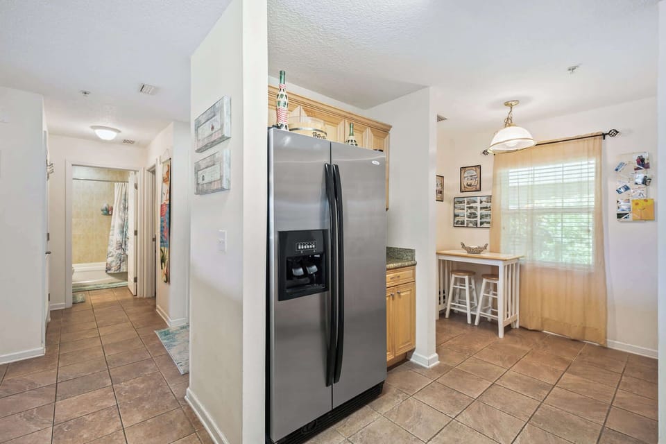 - Stainless steel refrigerator and bright cozy breakfast nook  
- Natural light fills this functional vacation condo kitchen  
- Perfect space to enjoy quick meals or morning coffee breaks 