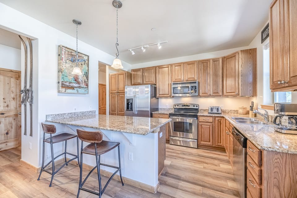 Kitchen - Granite counters, hardwood flooring, stainless steel appliances, and additional seating at the island.
